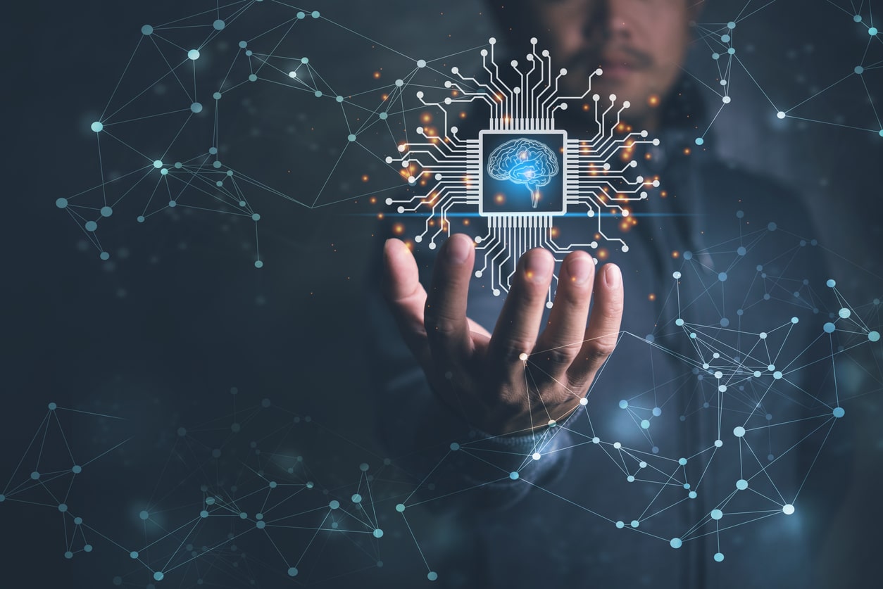 Uma mão estendida segura um chip de computador iluminado que exibe uma imagem do cérebro humano, representando a interseção do marketing digital e da inteligência artificial. O fundo é escuro, com pontos e linhas de conexão brilhantes, simbolizando redes e tecnologia.