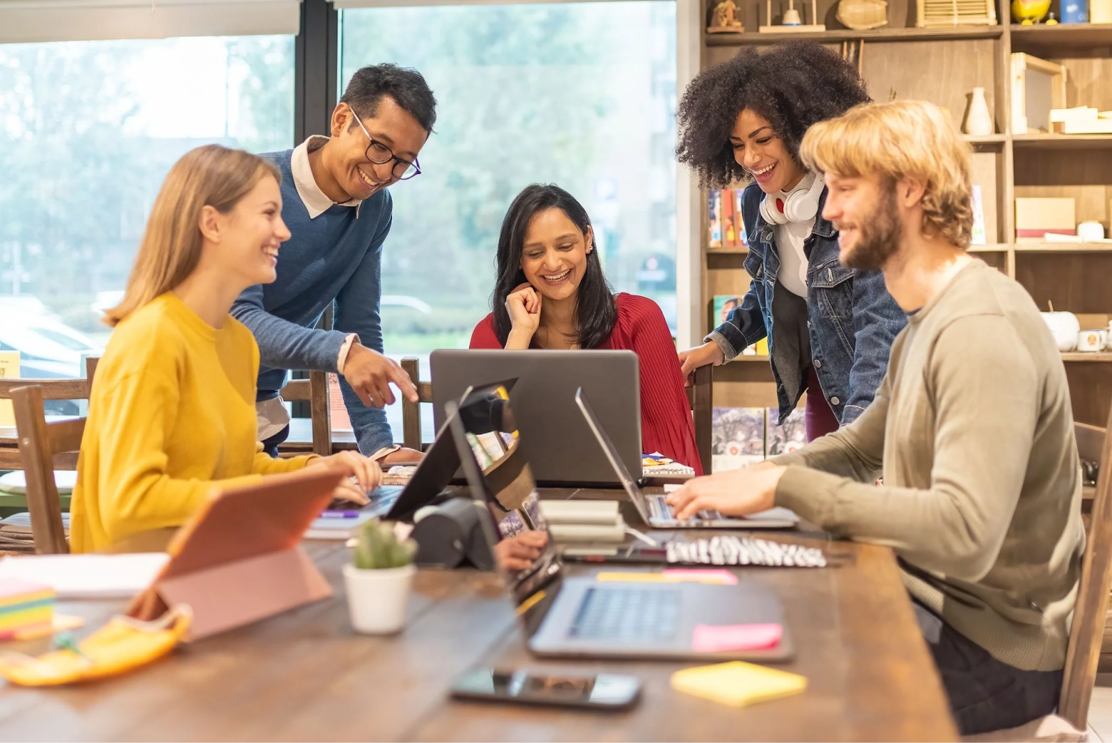 Um grupo de jovens empreendedores discutindo estratégias para alavancar seu negócio com Marketing Digital, utilizando laptops e tablets para planejar suas campanhas.