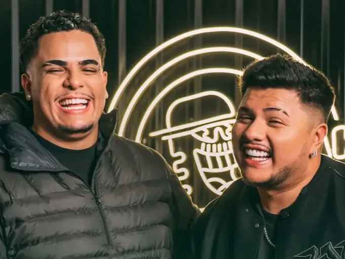 Dois amigos sorridentes comemorando o sucesso de sua parceria que gera renda extra. Com um letreiro iluminado ao fundo, eles demonstram a alegria de quem encontrou uma fonte de ganhos adicionais trabalhando juntos em projetos lucrativos.