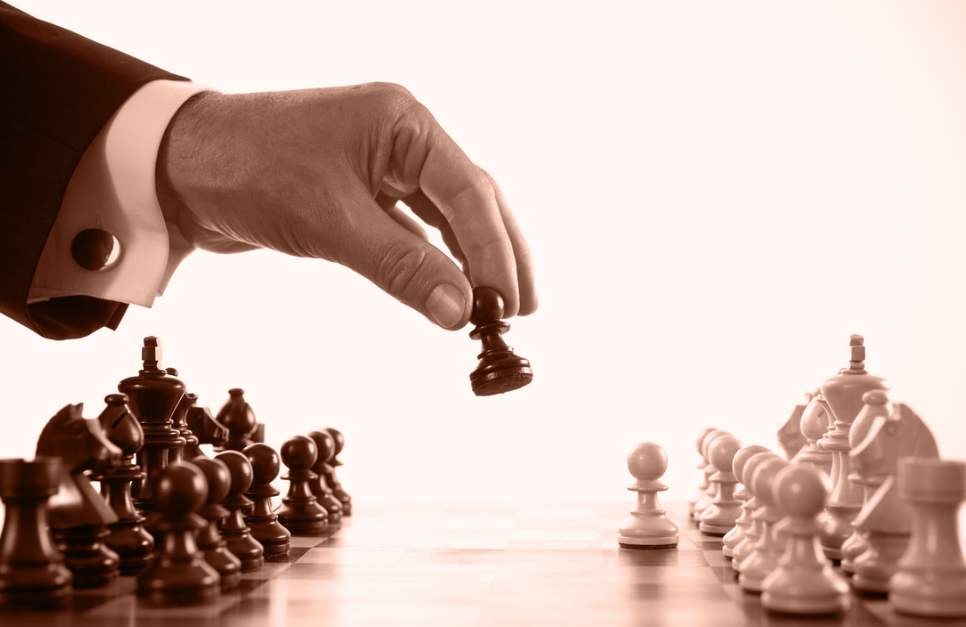 Mão posicionando uma peça no tabuleiro de xadrez, simbolizando movimentos táticos e estratégicos no networking de negócios.
