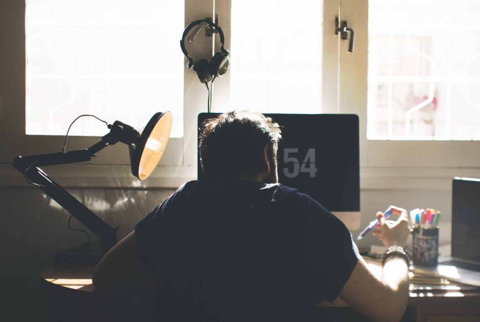Trabalhador noturno em home office focado no monitor, sugerindo dedicação e rotina produtiva como formas de descobrir como ganhar dinheiro remotamente.