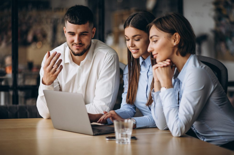Três profissionais reunidos em volta de um notebook, analisando informações juntos, ilustrando networking colaborativo no ambiente de trabalho.