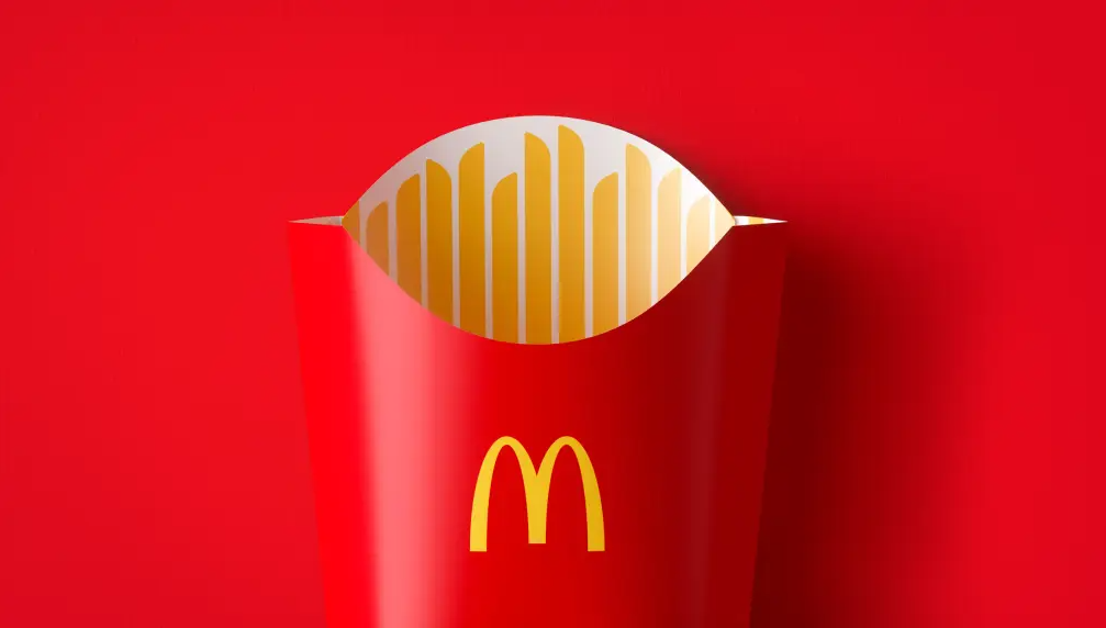 Embalagem de batatas fritas do McDonald's com fundo vermelho, destacando o branding icônico da marca através de suas cores e logotipo reconhecíveis globalmente.