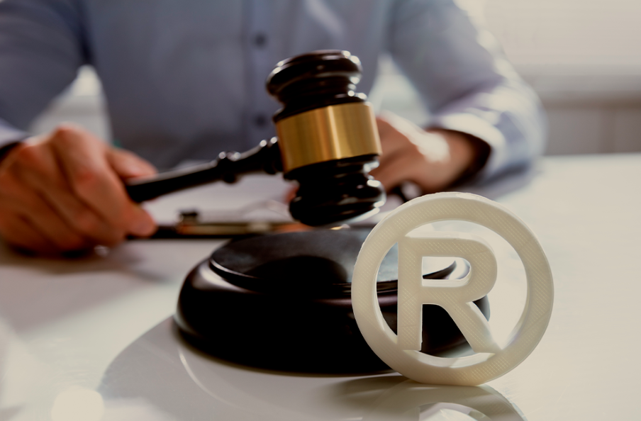 Símbolo de marca registrada ao lado de martelo de juiz, representando a importância da proteção legal no processo de branding e construção da identidade de marca.