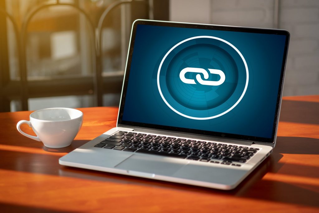 A imagem de um laptop com um ícone de link proeminente na tela, destaca a importância das conexões no ambiente online. Isso sugere que o conteúdo aborda como o 'Link building' é uma estratégia fundamental para o SEO, aumentando a relevância e a autoridade de um site através da construção de uma rede robusta de links.