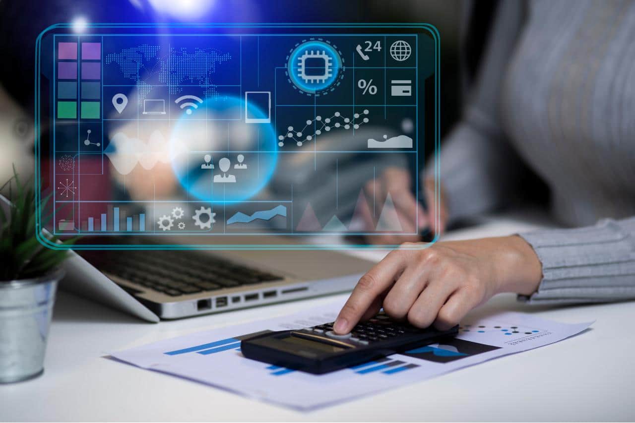 Pessoa utilizando calculadora ao lado de um notebook com gráficos digitais e ícones de análise de dados, representando o uso da automação de marketing para otimizar estratégias e decisões empresariais.
