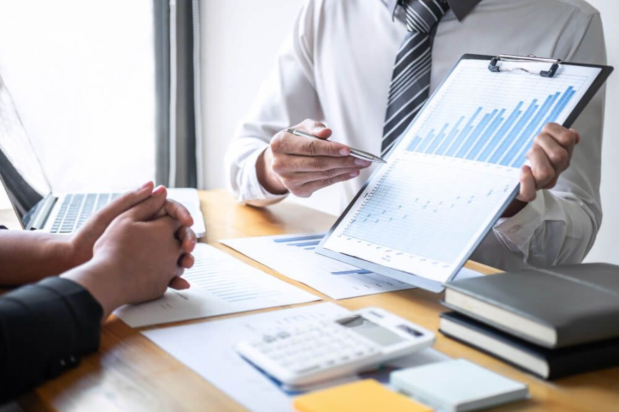 Profissionais analisam gráficos de desempenho em uma reunião, discutindo estratégias para aumentar as vendas de produtos digitais e otimizar resultados no mercado online.