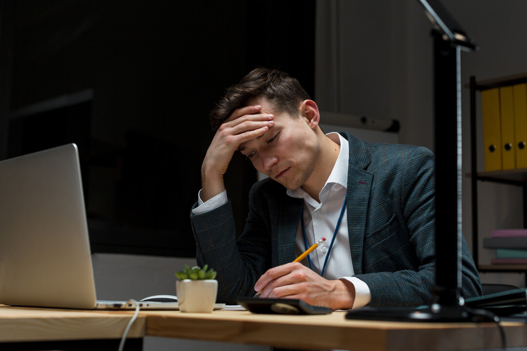 Homem estressado trabalhando à noite em frente ao computador, simbolizando a frustração de negócios que não utilizam estratégias eficazes de remarketing.