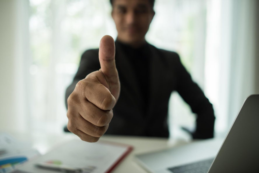 Profissional sorridente faz sinal de positivo, indicando sucesso na aplicação do funil de vendas e aumento na conversão de clientes.