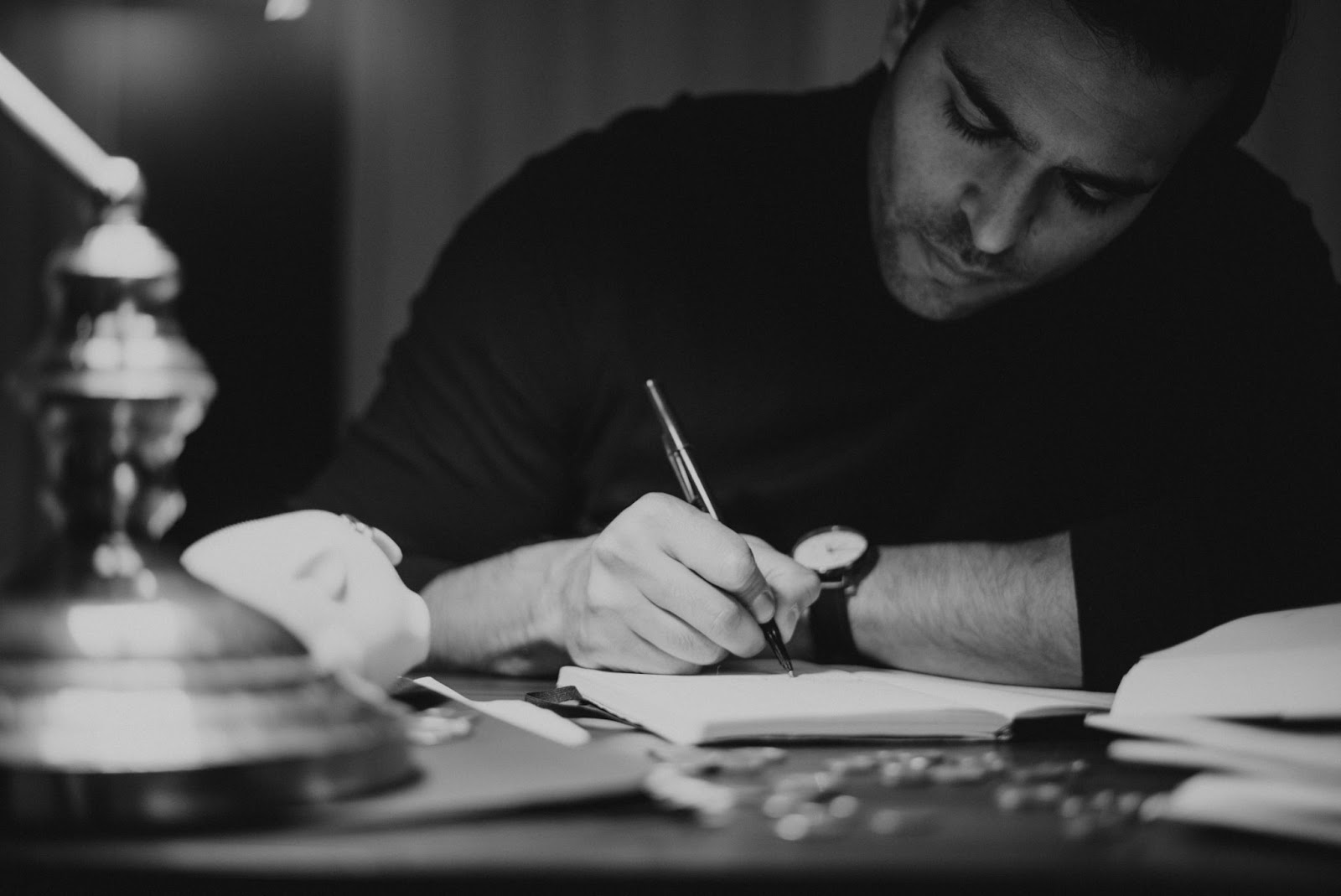 A imagem de um homem imerso na escrita manual, com foco na caneta e no caderno, destaca a importância da elaboração cuidadosa do texto. Isso sugere que o conteúdo aborda a arte e a técnica de criar 'copy' que engaja, informa e persuade o público.