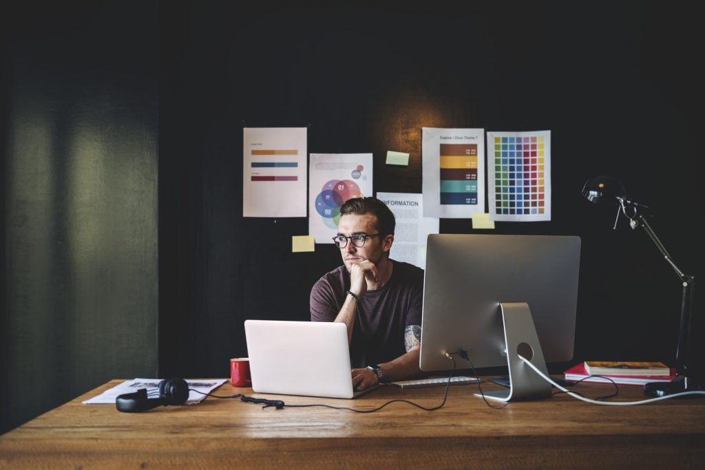 A imagem de um designer ou criativo em seu espaço de trabalho, cercado por referências e ferramentas, destaca a autonomia. Isso sugere que o conteúdo aborda a jornada de um 'freelancer' que busca inspiração e controle sobre seus projetos, moldando sua própria carreira.