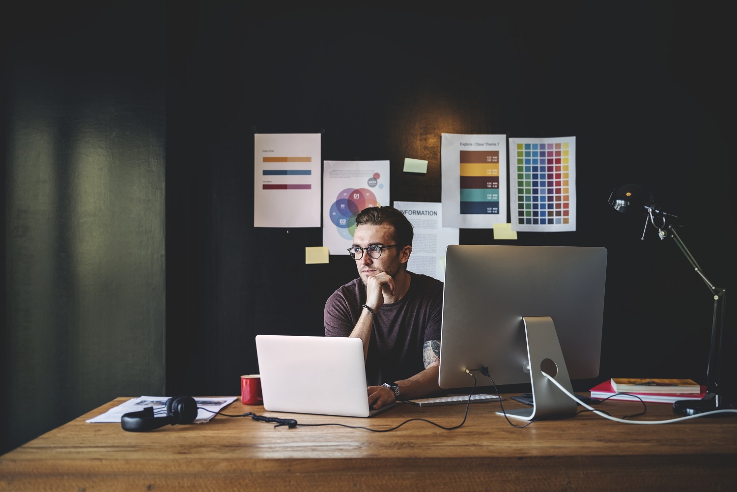 A imagem de um designer ou criativo em seu espaço de trabalho, cercado por referências e ferramentas, destaca a autonomia. Isso sugere que o conteúdo aborda a jornada de um 'freelancer' que busca inspiração e controle sobre seus projetos, moldando sua própria carreira.