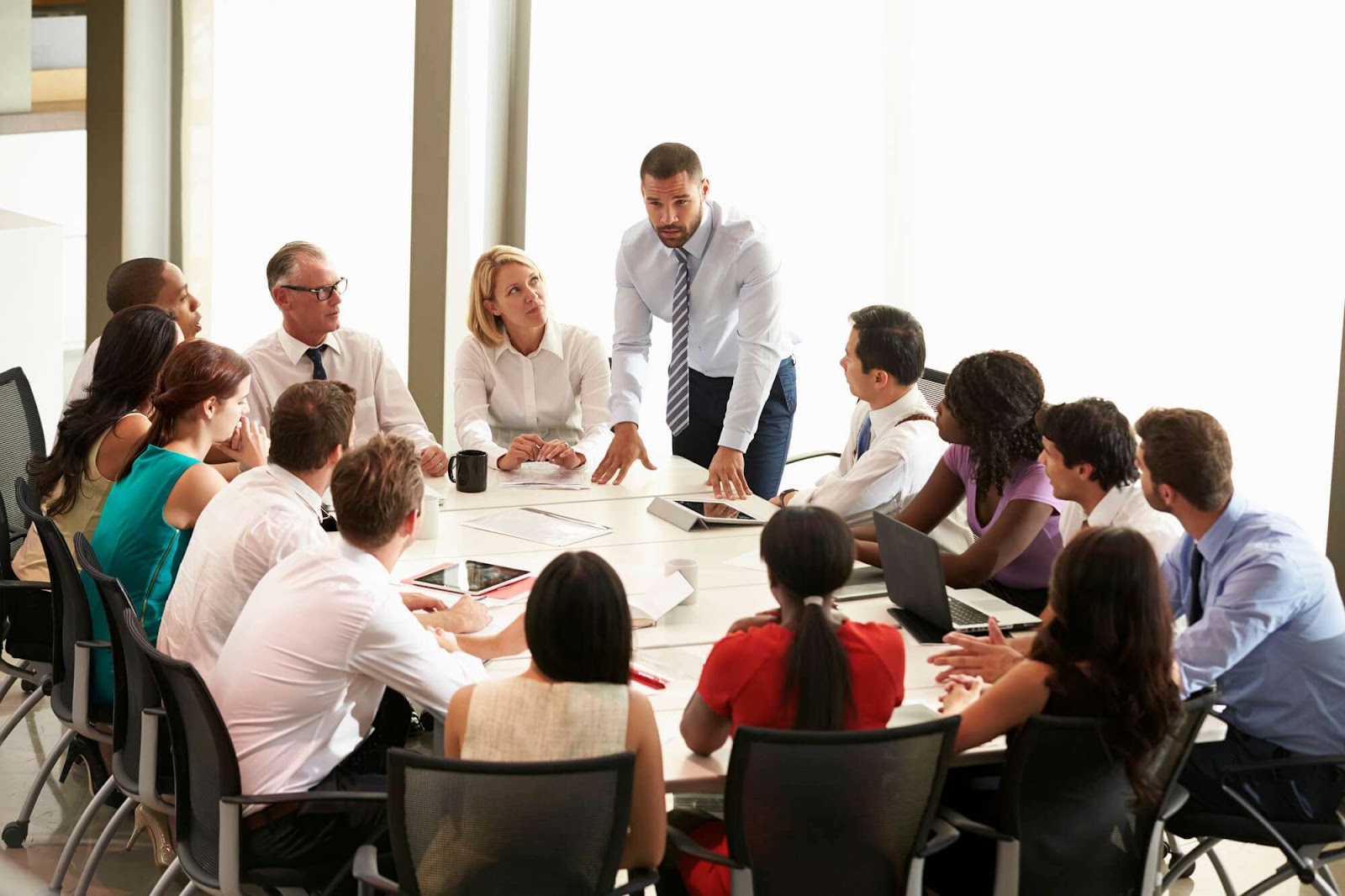 Grupo de profissionais reunidos em uma sala de conferência, discutindo estratégias e soluções para campanhas de marketing digital. A cena transmite colaboração, troca de ideias e planejamento, elementos fundamentais para o desenvolvimento de ações eficientes no ambiente online.