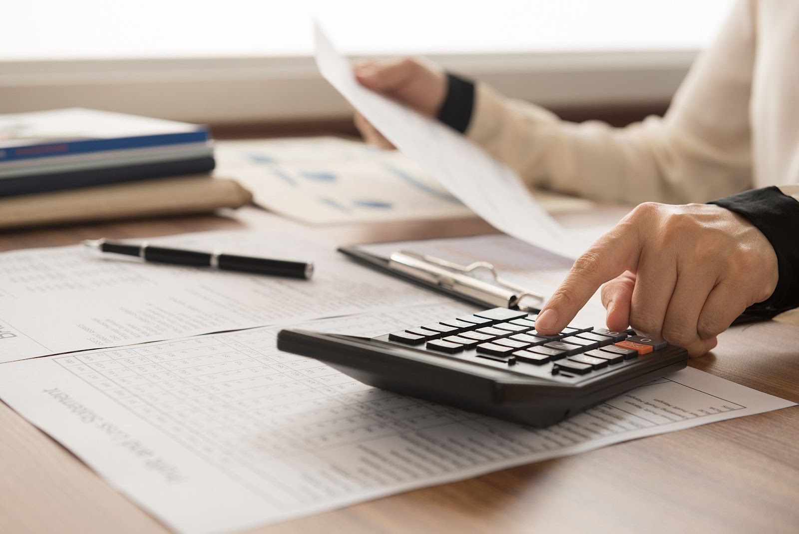 A imagem de alguém realizando cálculos e analisando documentos financeiros, destaca a necessidade de precisão na gestão de investimentos. Isso sugere que o conteúdo aborda como o PPC é uma estratégia que demanda controle financeiro rigoroso para maximizar a rentabilidade, garantindo que cada clique seja um investimento inteligente.