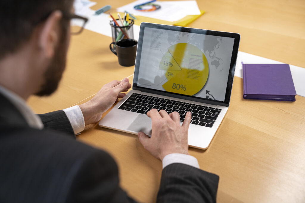 A imagem de um profissional analisando dados de mercado e gráficos em um laptop, destaca a importância da estratégia e da adaptação. Isso sugere que o conteúdo aborda como um 'produto digital' precisa ser constantemente avaliado e ajustado com base em insights de mercado para atender às demandas do público e garantir sua competitividade e crescimento.