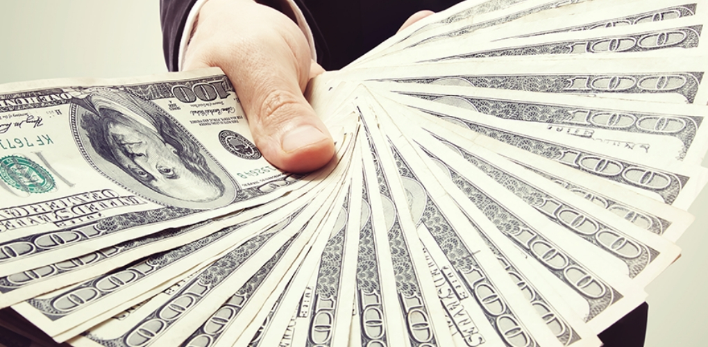 Grande quantidade de dinheiro sendo exibida por uma mão. Isso simboliza a capacidade de um 'produto digital' de gerar riqueza e um alto retorno financeiro.