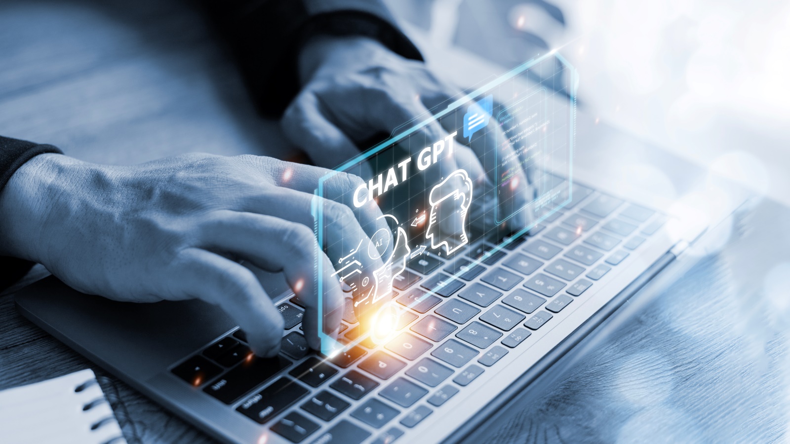 Mãos digitando em um laptop com uma projeção de 'CHAT GPT' e ícones de comunicação. Ilustra a interação com o Chat GPT como uma ferramenta de inteligência artificial para geração de texto.