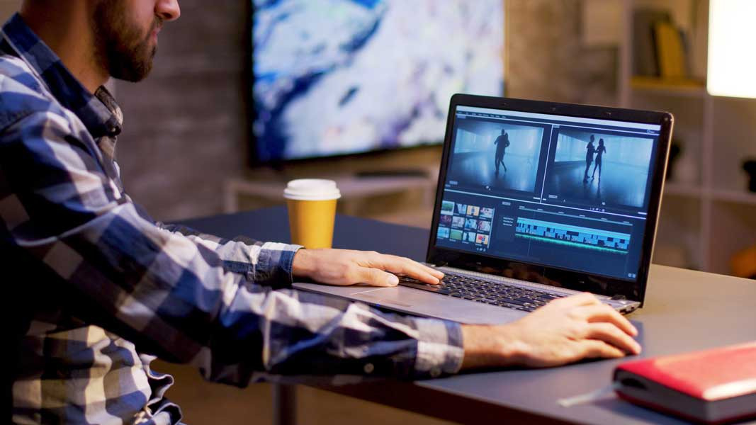 Cena de edição de vídeo em um laptop, com pessoa concentrada no trabalho. Isso simboliza o esforço na criação de conteúdo de vídeo de alta qualidade e a importância de uma VSL bem produzida.