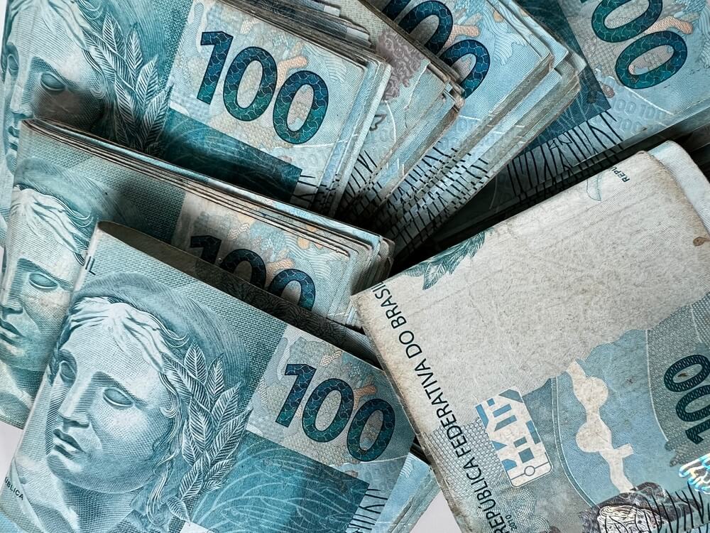 Notas de 100 reais espalhadas, representando dinheiro e lucro. A imagem pode ser associada a estratégias e resultados de vendas no Telegram.