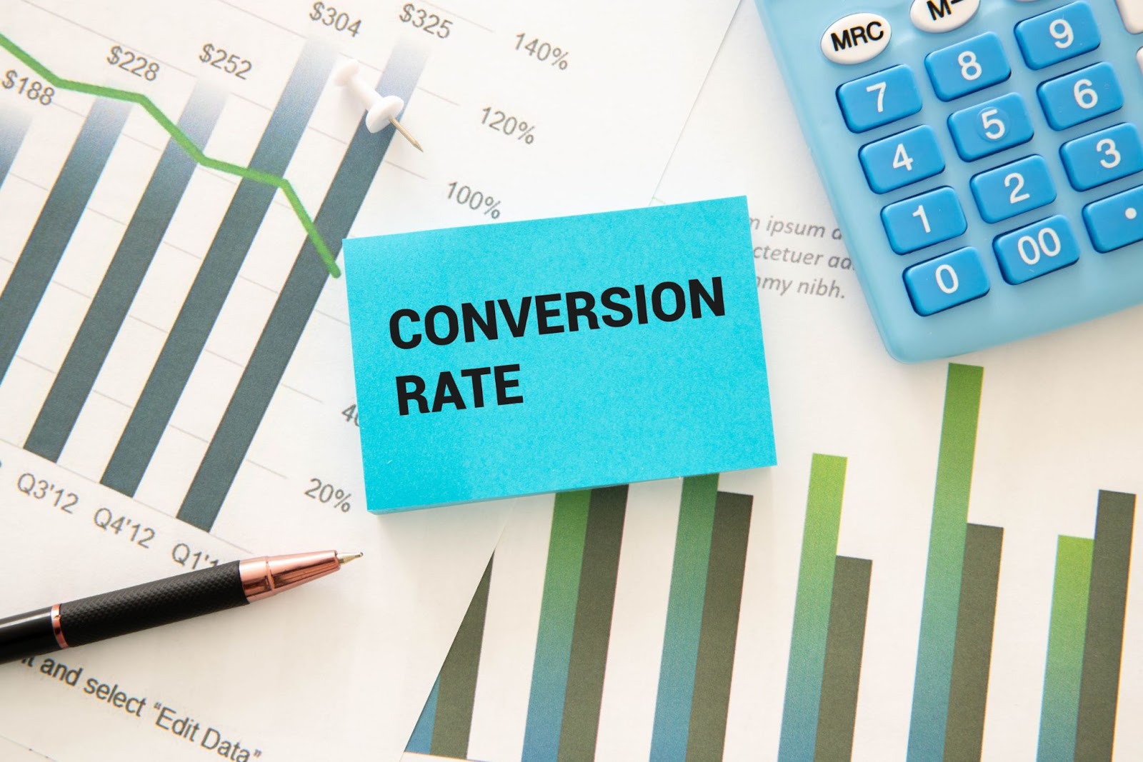 Gráficos financeiros e uma calculadora em uma mesa de trabalho, com um post-it que lê 'CONVERSION RATE'. A capacidade de converter visitantes em leads (e depois em clientes) é diretamente influenciada pela qualidade e relevância de um Lead Magnet.